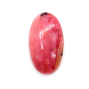 May include: Oval-shaped pink gemstone with a polished surface. The stone has a mix of light and dark pink hues, with some areas appearing translucent. Small black inclusions are visible near the top of the stone. The gemstone is set against a white background.