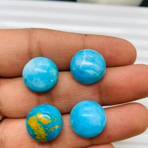 May include: Four round cabochon gemstones, two are blue with white swirls, one is blue with yellow and brown swirls, and one is solid blue.