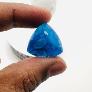 May include: A triangular blue agate cabochon with white swirls and a glossy finish.