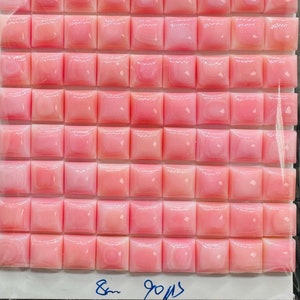 May include: A sheet of pink square tiles with a white background. The tiles are made of mother of pearl and have a slight iridescent sheen. The sheet measures 8 inches by 9 inches.