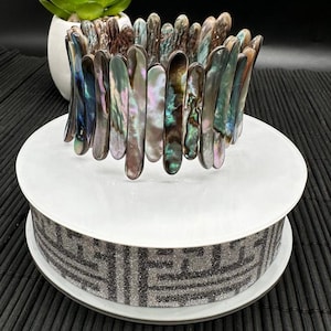 May include: A bracelet made of iridescent abalone shell pieces. The pieces are arranged in a staggered pattern, creating a unique and eye-catching design.