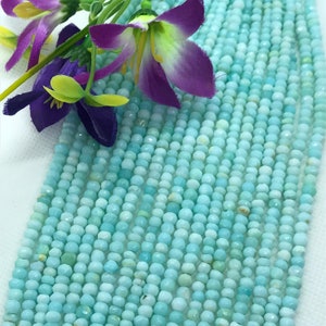 May include: A strand of light blue opal beads. The beads are faceted and have a slightly irregular shape. The beads are strung on a clear thread.