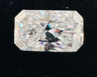 Könnte beinhalten: Ein klarer, rechteckiger, facettierter Edelstein mit Brillantschliff. Der Edelstein ist vor einem schwarzen Hintergrund platziert.