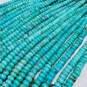 May include: A strand of turquoise beads, each bead is a light blue color with dark blue and brown marbling. The beads are round and smooth.