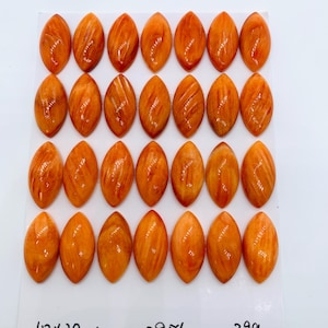 May include: Twenty-eight orange marquise-shaped cabochons with a marbled texture arranged in four rows of seven. The white card displays the text 10x20mm, 28pcs, and 39g, indicating the size, quantity, and weight of the pieces.