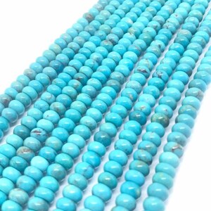 Puede incluir: Una hebra de cuentas de turquesa, cada cuenta es de color azul claro con una forma redonda y lisa.
