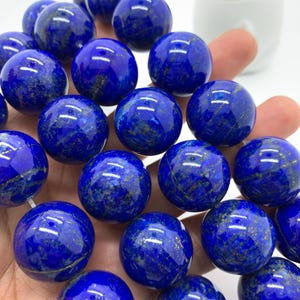 Puede incluir: Una hebra de cuentas redondas de lapislázuli azul con motas doradas. Las cuentas tienen un diámetro aproximado de 2,5 cm.