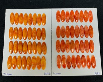 Könnte beinhalten: Zwei Sätze ovaler, orangefarbener Edelsteine, angeordnet auf weißen Karten. Jeder Edelstein misst 7x20mm. Die Karten sind mit der Menge von je 32 Stück beschriftet. Die Edelsteine haben ein poliertes, durchscheinendes Aussehen.