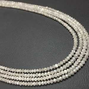May include: A strand of white diamond beads, strung together to form a necklace. The beads are faceted and have a rough, unpolished look.