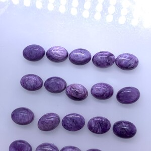 May include: Twenty oval-shaped purple gemstones with a swirling pattern.