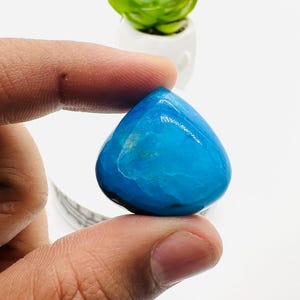 May include: A teardrop-shaped blue gemstone with a smooth, polished surface.