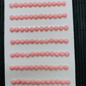 May include: Rows of small, light pink beads, each approximately 5mm in diameter, are arranged on a white card. The card has the text "5mm" and "84pcs" in the bottom corners. The beads are evenly spaced and appear to be a uniform size and color.