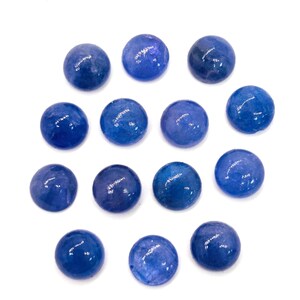May include: A collection of fourteen round, polished blue gemstones. The stones vary slightly in shade, with some appearing a deeper, richer blue than others. The gemstones are arranged against a plain white background.