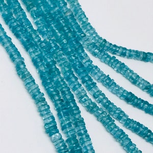May include: A strand of light blue aquamarine beads, each bead is faceted and has a square shape.