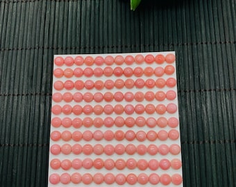 Könnte beinhalten: Eine Ansammlung von 132 rosa Cabochon-Edelsteinen, jeweils etwa 6 mm im Durchmesser, auf einer weißen Karte angeordnet. Die Edelsteine haben eine weiche, einheitliche rosa Farbe. Auf der Karte steht auch die Nummer 289.