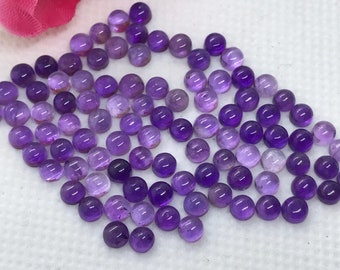 May include: A collection of round, purple amethyst cabochons. The cabochons are smooth and polished, with a slight variation in color.