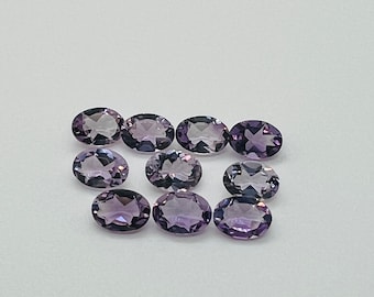 May include: Ten oval-shaped amethyst gemstones, ranging in size and shade of purple.