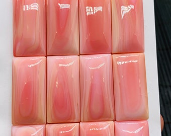 May include: Twelve pink and white shell cabochons, each measuring 1.5 x 3.0 inches, arranged in three rows of four.