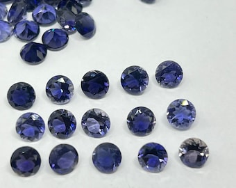 May include: A collection of 17 round, dark blue gemstones, arranged in a grid pattern on a white surface.
