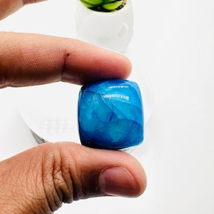 May include: A blue, square-shaped, polished agate stone with white veins and a smooth, glossy finish.