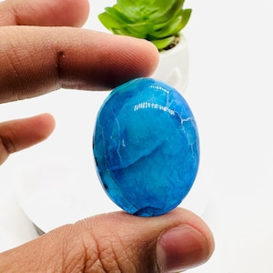 May include: A smooth, oval-shaped blue agate gemstone with white veins and a glossy finish.