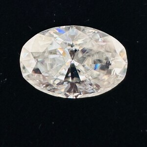 May include: A clear oval-shaped diamond with facets that reflect light.