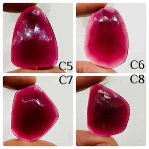 May include: Four close-up images of a deep red gemstone with a faceted cut. The gemstone is held in a hand, and the images show the gemstone from different angles.