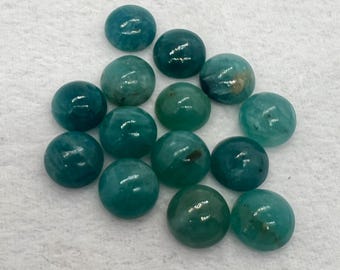 May include: A collection of 15 teal green cabochon gemstones, each with a smooth, rounded surface. The stones are arranged in a loose cluster on a white background.