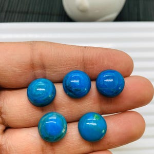 May include: Five round, blue and green cabochon gemstones. The gemstones are smooth and polished.