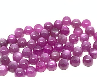 May include: A collection of round, cabochon-cut, purple gemstones. The stones are smooth and polished, with a slight shimmer.