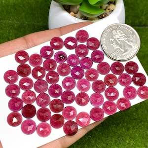 May include: A collection of 50 round, faceted, red gemstones. The gemstones are approximately 6mm in diameter and have a polished finish.