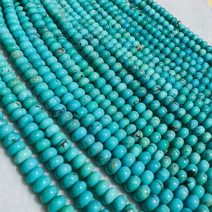May include: A strand of turquoise beads, each bead is a light blue color with dark blue and brown veins. The beads are round and smooth, and they are arranged in a row.