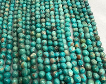 May include: A collection of turquoise beads, varying in shade from light teal to deep sea green. The beads, a mix of round and oval shapes, display natural brown and tan markings. Strung together, these beads are ready for crafting jewellery. The image shows a close-up of the beads.