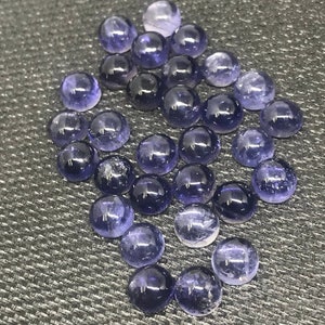 May include: A collection of round, purple gemstones. The gemstones are smooth and polished, with a slight shimmer.