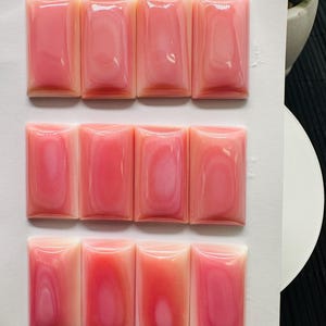 May include: Nine pink shell cabochons arranged in three rows of three. Each cabochon is rectangular with rounded edges and measures 14 x 26 mm.
