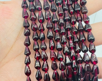 May include: A strand of deep red garnet gemstone beads, each bead is faceted and shaped like a teardrop. The beads are strung on a clear thread and are ready to be used for jewelry making.