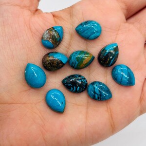 May include: A collection of ten teardrop-shaped turquoise gemstones. The stones vary in color, with some displaying solid turquoise hues and others featuring brown, gold, and black veining. The gemstones are smooth and polished, ideal for jewelry making or collecting.