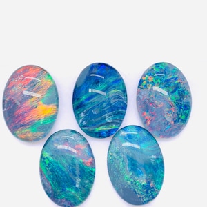 Könnte beinhalten: Fünf ovale Opale mit einer Vielzahl von blauen, grünen und orangefarbenen, schillernden Farben. Die Opale sind vor einem weißen Hintergrund angeordnet.