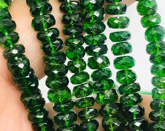 Puede incluir: Una hebra de cuentas de piedras preciosas facetadas de color verde oscuro. Las cuentas son redondas y tienen un acabado liso y pulido.