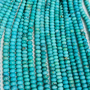 May include: A strand of turquoise beads, each bead is a light blue color with dark brown and black marbling. The beads are round and smooth.