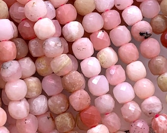 May include: A strand of pink opal beads, each bead is faceted and has a slightly different shade of pink. The beads are all approximately the same size and are strung on a clear thread.