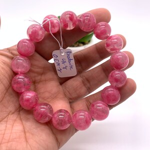 May include: A pink rhodochrosite bracelet with round beads. The tag reads "Rhodochrosite 16-8" and "OEM-3".