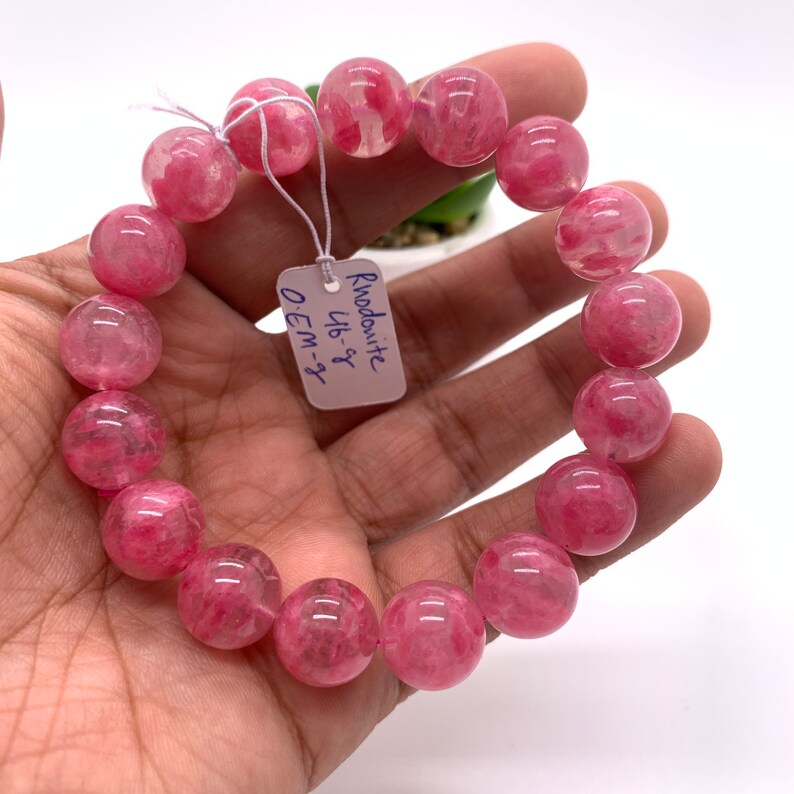 May include: A pink rhodochrosite bracelet with round beads. The tag reads "Rhodochrosite 16-8" and "OEM-3".