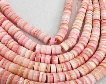 May include: A strand of pink and white shell beads. The beads are round and have a layered, striated appearance.