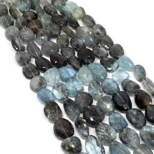 May include: A strand of light blue aquamarine gemstone beads with a faceted oval shape. The beads are translucent and have a slight shimmer.