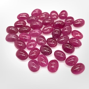 Puede incluir: Una colecci&oacute;n de piedras preciosas de rub&iacute; rosa de forma ovalada. Los rub&iacute;es son lisos y pulidos, con un ligero brillo.