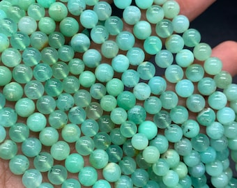May include: A strand of green gemstone beads. The beads are round and smooth, with a slightly translucent appearance. The beads are strung on a clear thread.