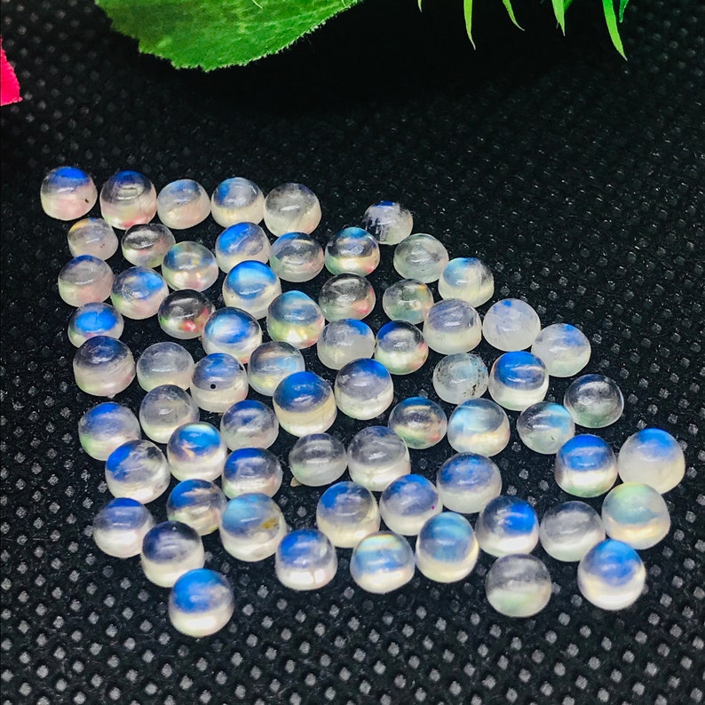 May include: A collection of round, iridescent moonstone cabochons. The stones are a milky white color with a blue sheen.