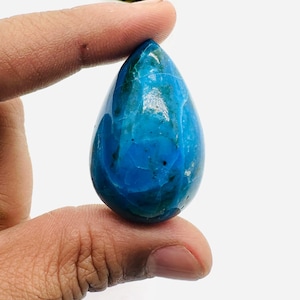 May include: A teardrop-shaped blue and green gemstone pendant. The pendant is smooth and polished, with a light blue colour and green veins.