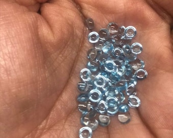 May include: A pile of small, round, light blue gemstones with a silver rim.